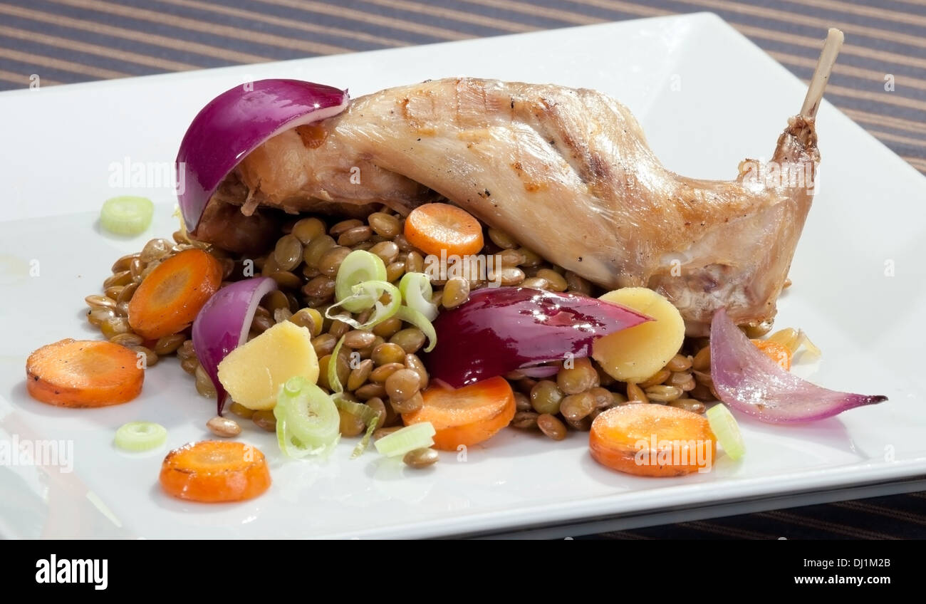 Baked rabbit leg with lentil and vegetable garnish Stock Photo - Alamy
