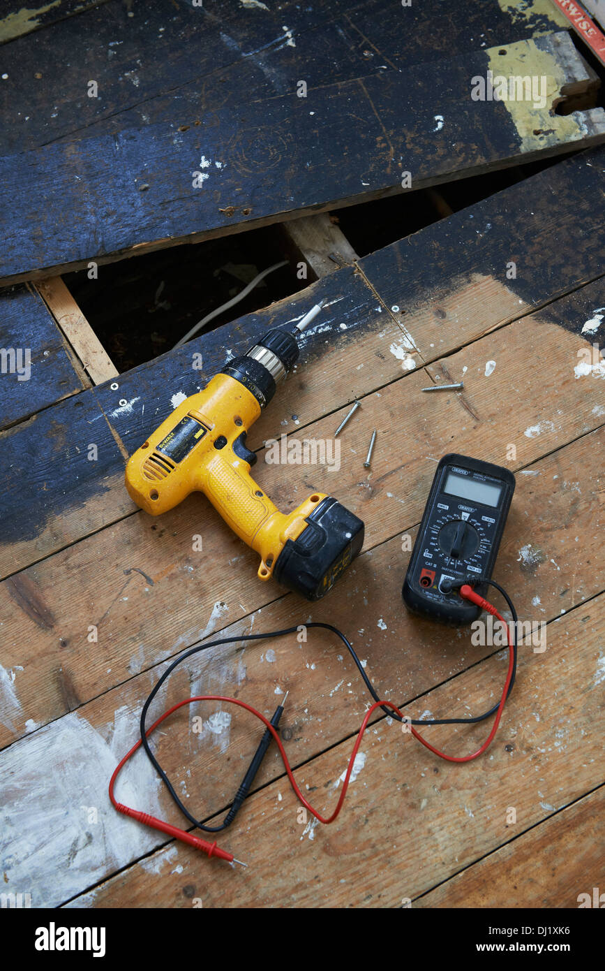 yellow cordless drill and multi meter on a bare floor ...
