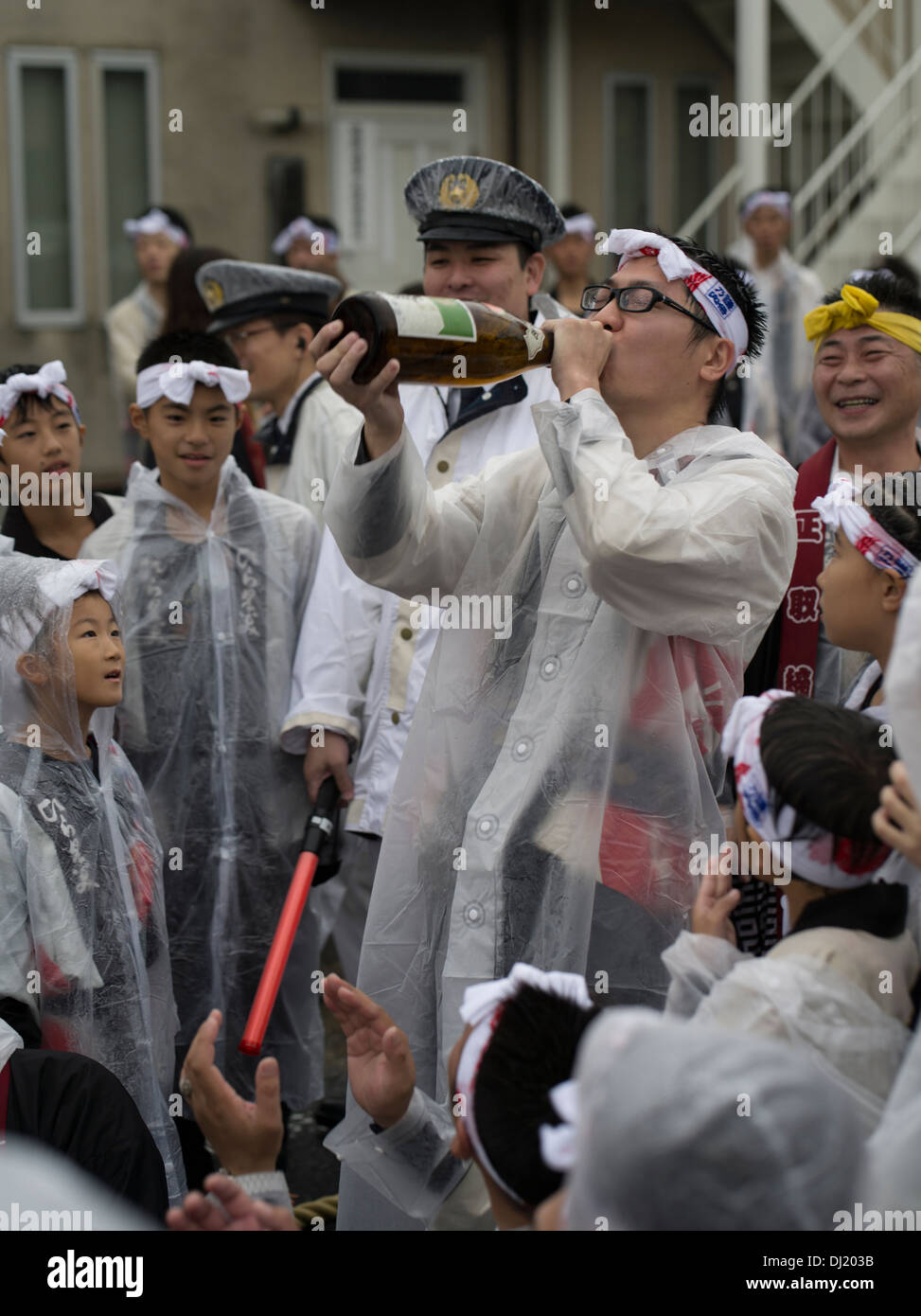 Man Drinking Sake as police and children watch, Karatsu Kunchi Festival, Karatsu City, Saga Prefecture, Japan Stock Photo