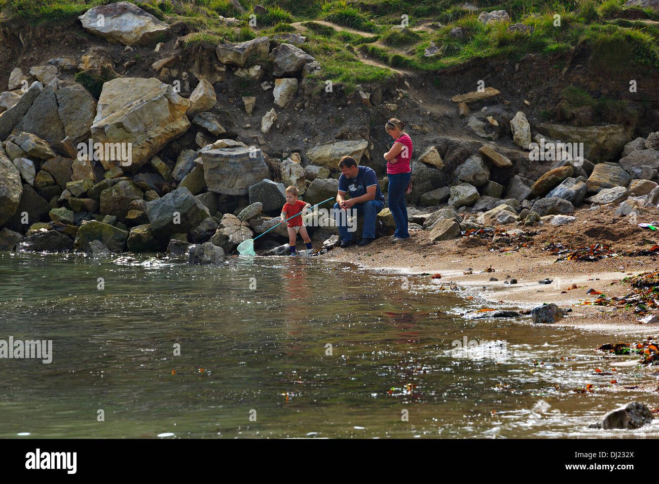 Crab fishing on the beach at Lulworth Cove, Dorset. Parents watch while