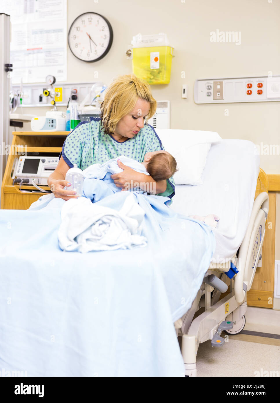 Mother Looking At Newborn Baby While Sitting In Hospital Bed Stock Photo