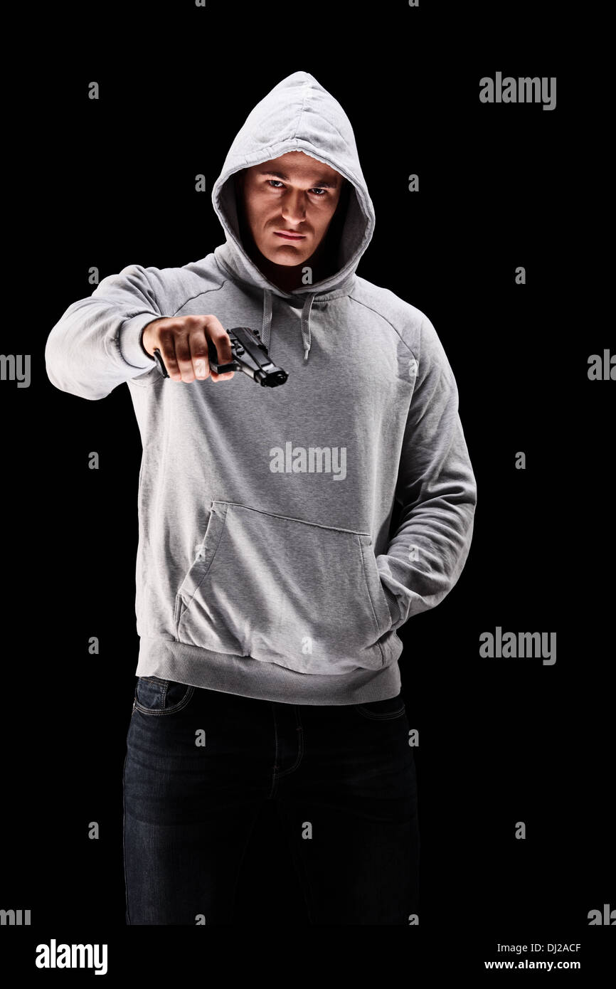 Young man with hood over his head holding a gun symbolizing crime Stock Photo