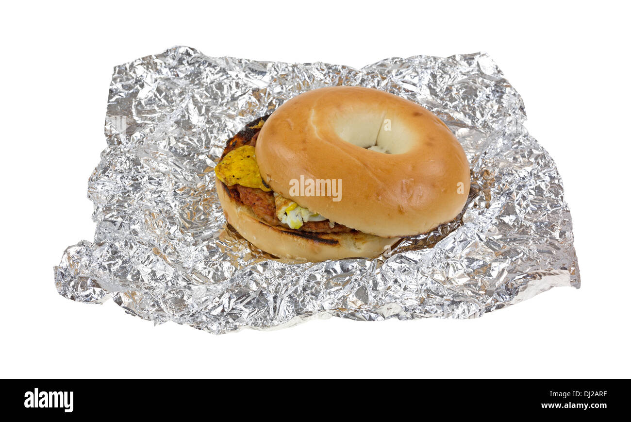 A breakfast bagel slightly opened upon crinkled aluminum foil. Stock Photo