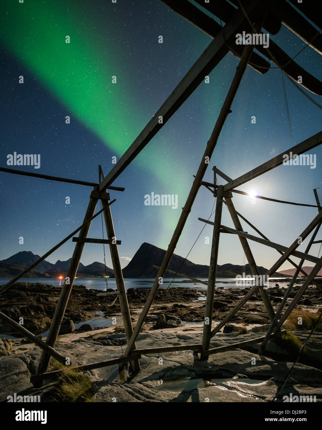 Northern Lights shine in sky over empty cod stockfish drying racks