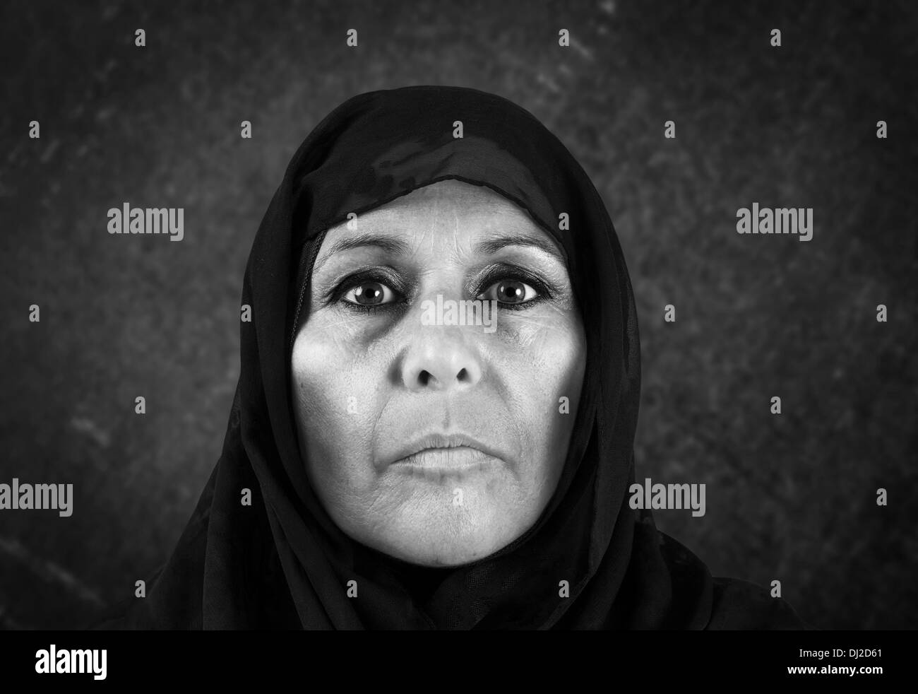 Dramatic blackand white portrait of serious middle aged muslim woman with black scarf or hijab Stock Photo