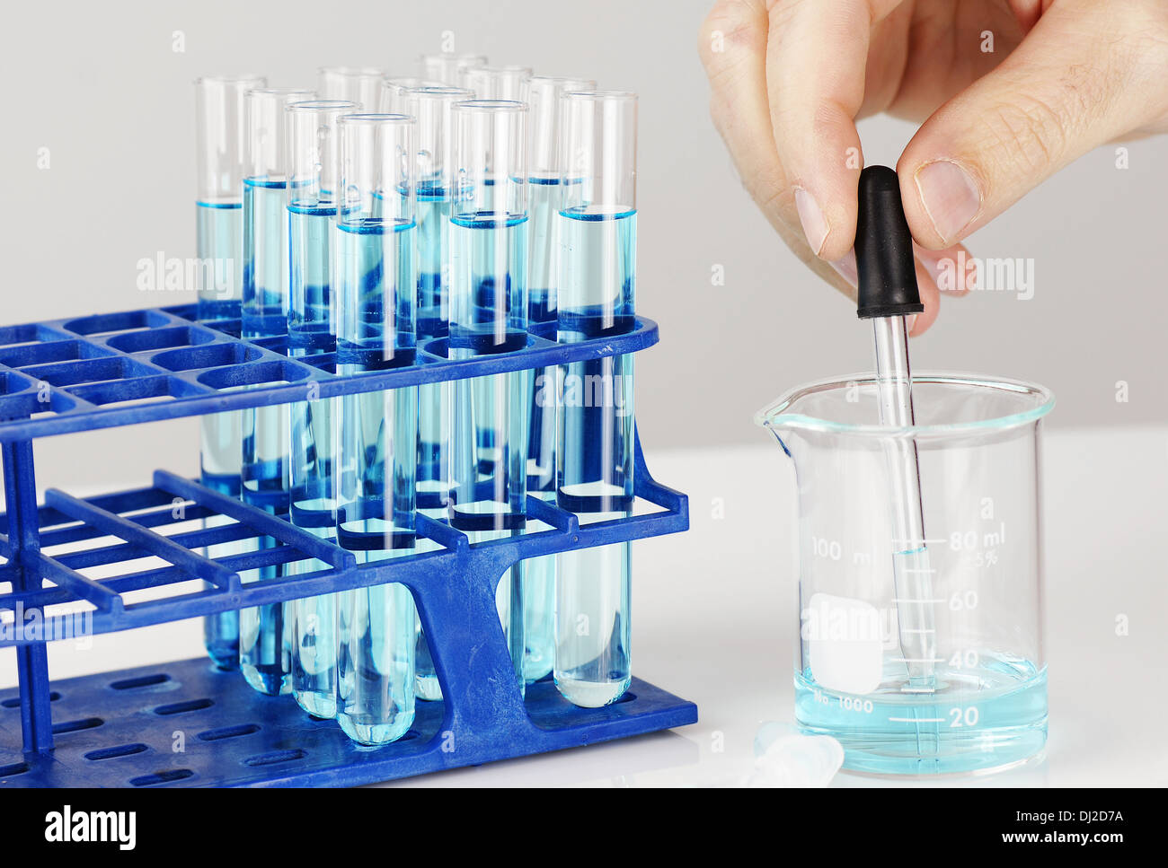 Test tubes with blue liquid, man hand with dropper chemistry, biology