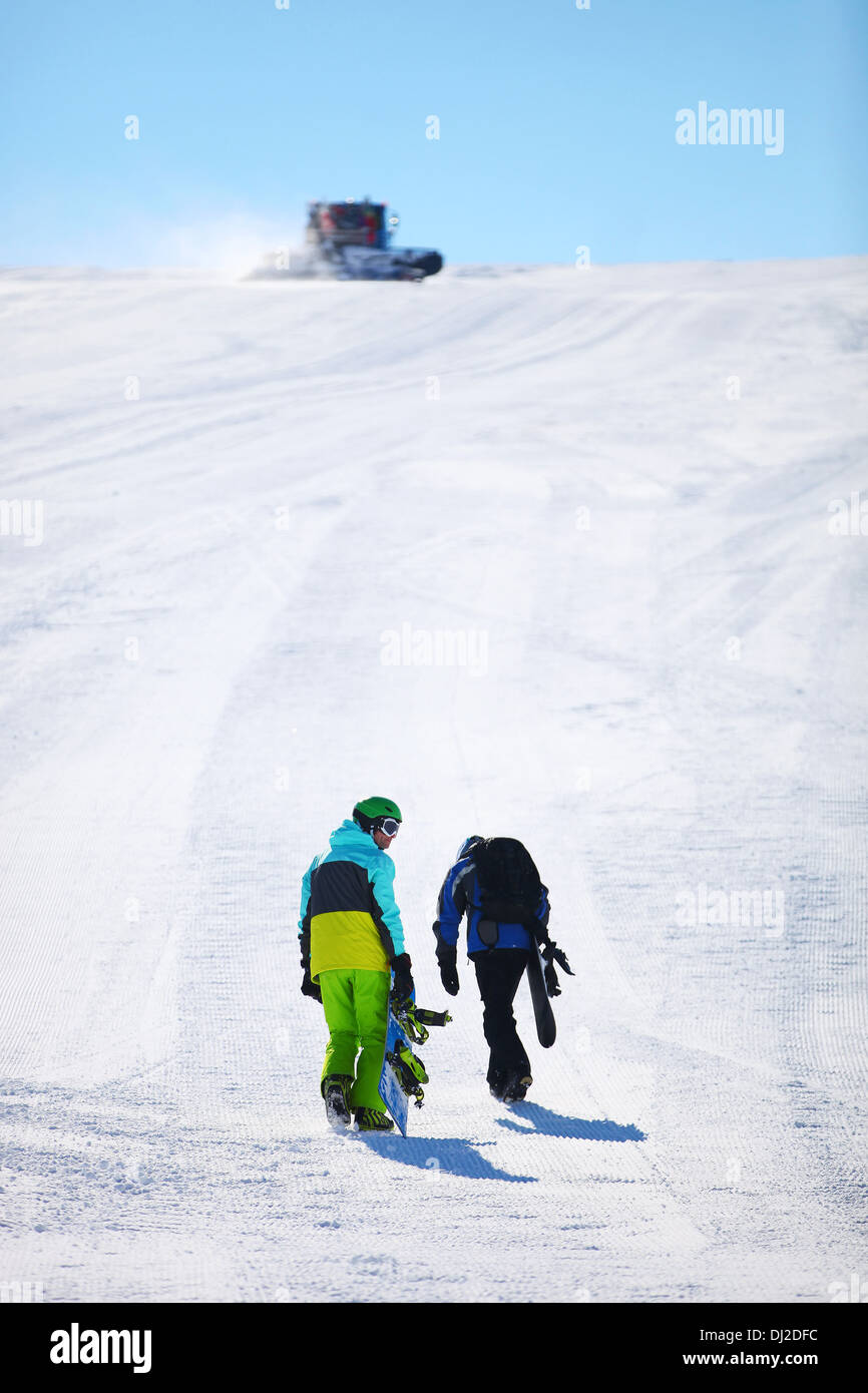 Two snowboarders walking up slope Stock Photo