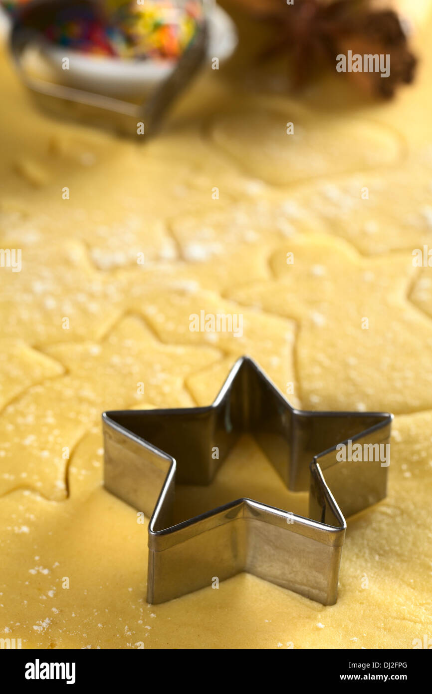 Star-shaped cookie cutter and other Christmas shapes cut into dough (Selective Focus) Stock Photo