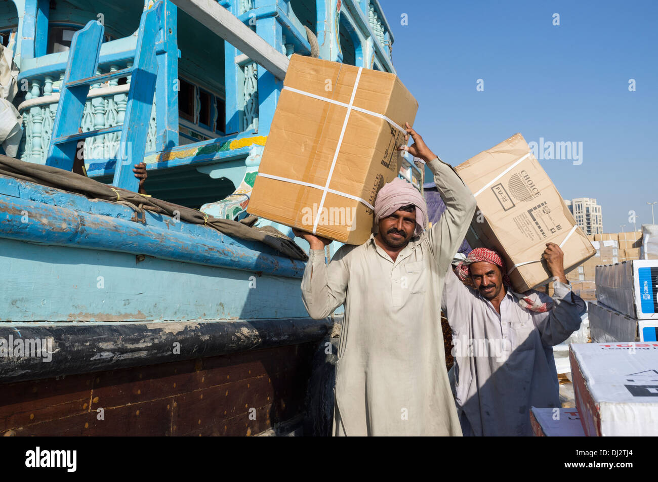Men loading cargo onto dhows at cargo wharf on The Creek in Dubai United Arab Emirates Stock Photo