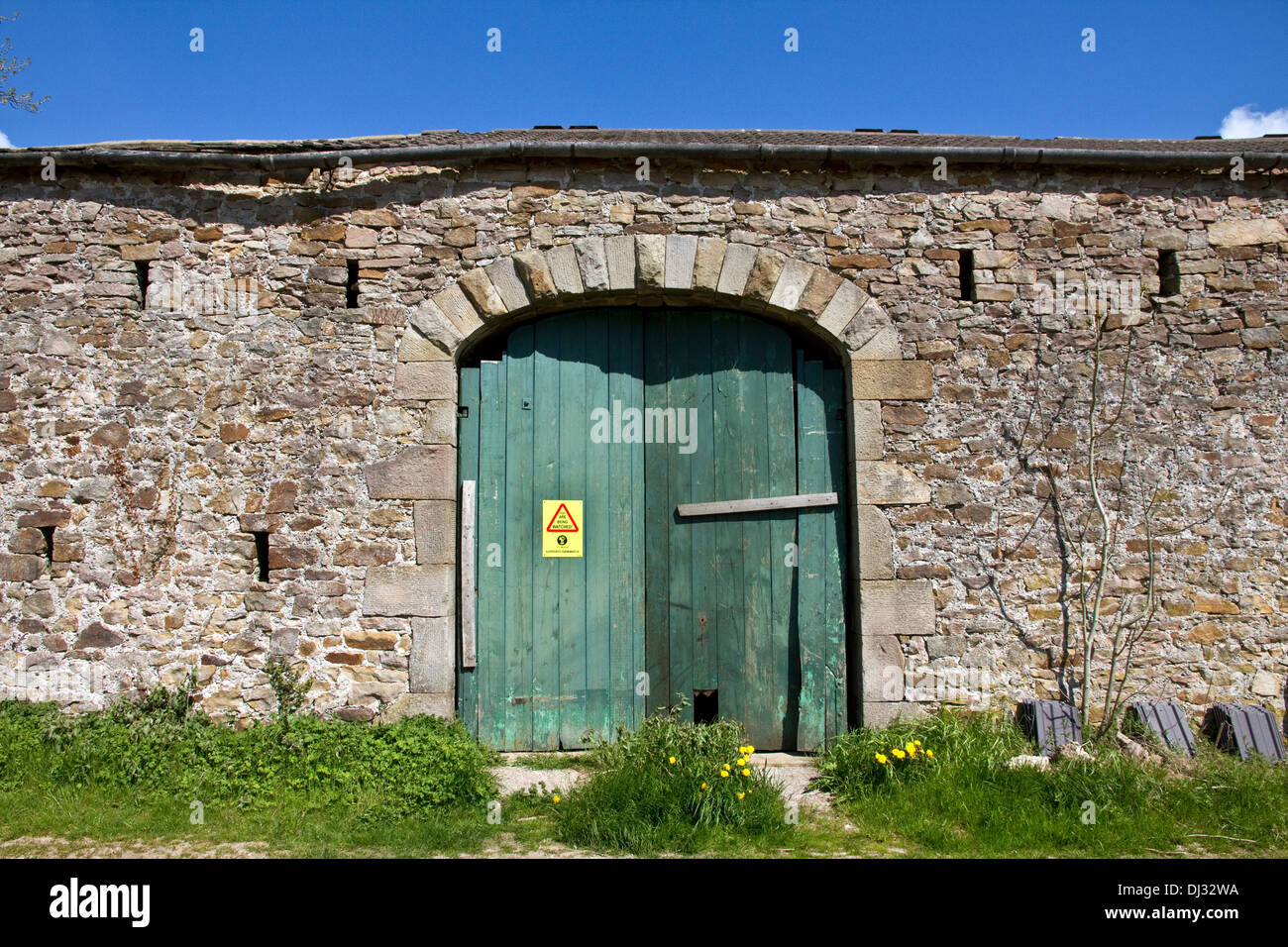 Rural stone barn with 'Farmwatch' notice ( to deter thefts) on wooden doors Stonyhurst, Ribble Valley, Lancashire, England, UK Stock Photo