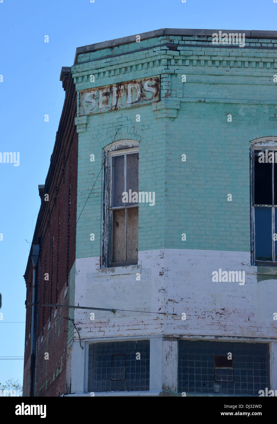 Old seed sign writing fades from the corner of a shut store, Carthage