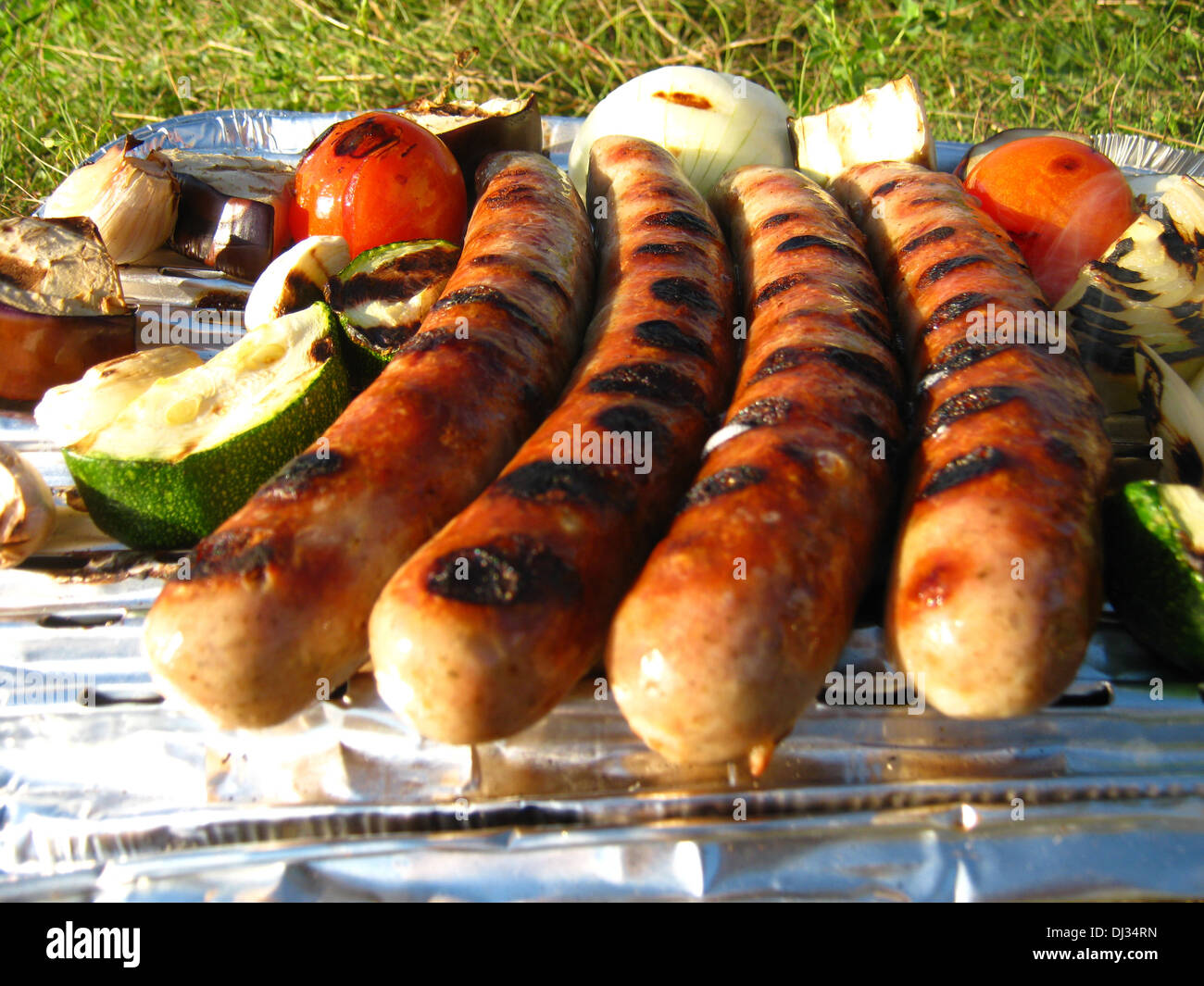 a disposable grill with roasting sausages and grilled vegetables Stock