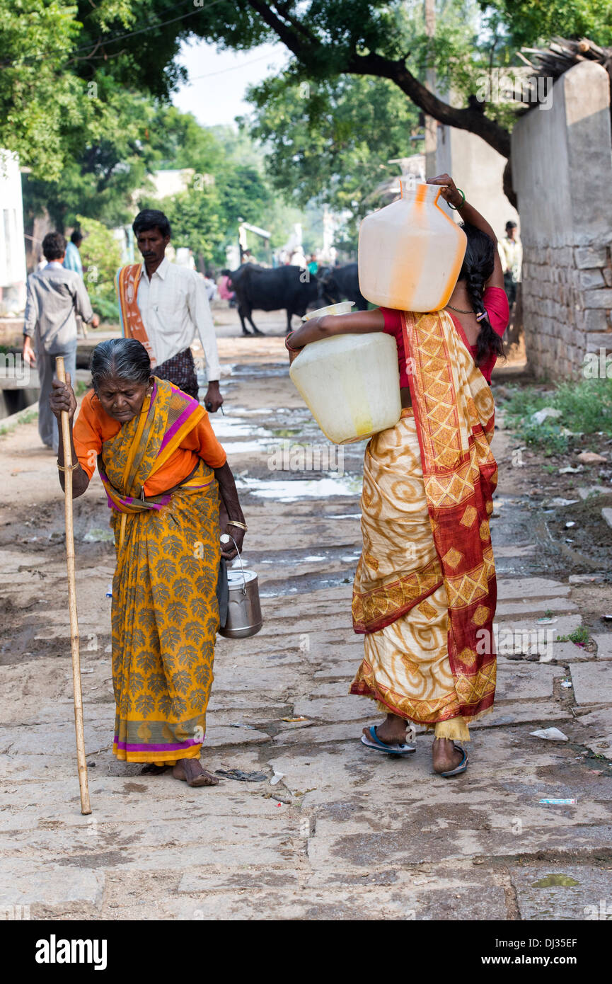 Indian woman plastic water pots from a standpipe in a rural Indian village street. Andhra Pradesh, India Stock Photo