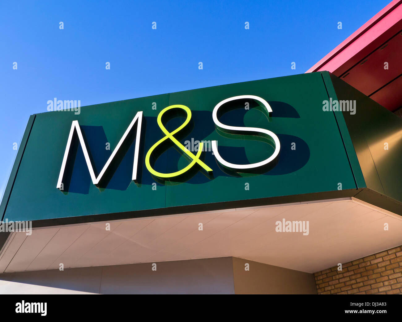 M&S Exterior Sign Sun Close view on sunlit M&S logo outside a UK superstore with clear blue sky behind Stock Photo