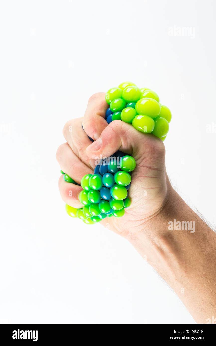 Male hand squeezing stress ball over plain background Stock Photo