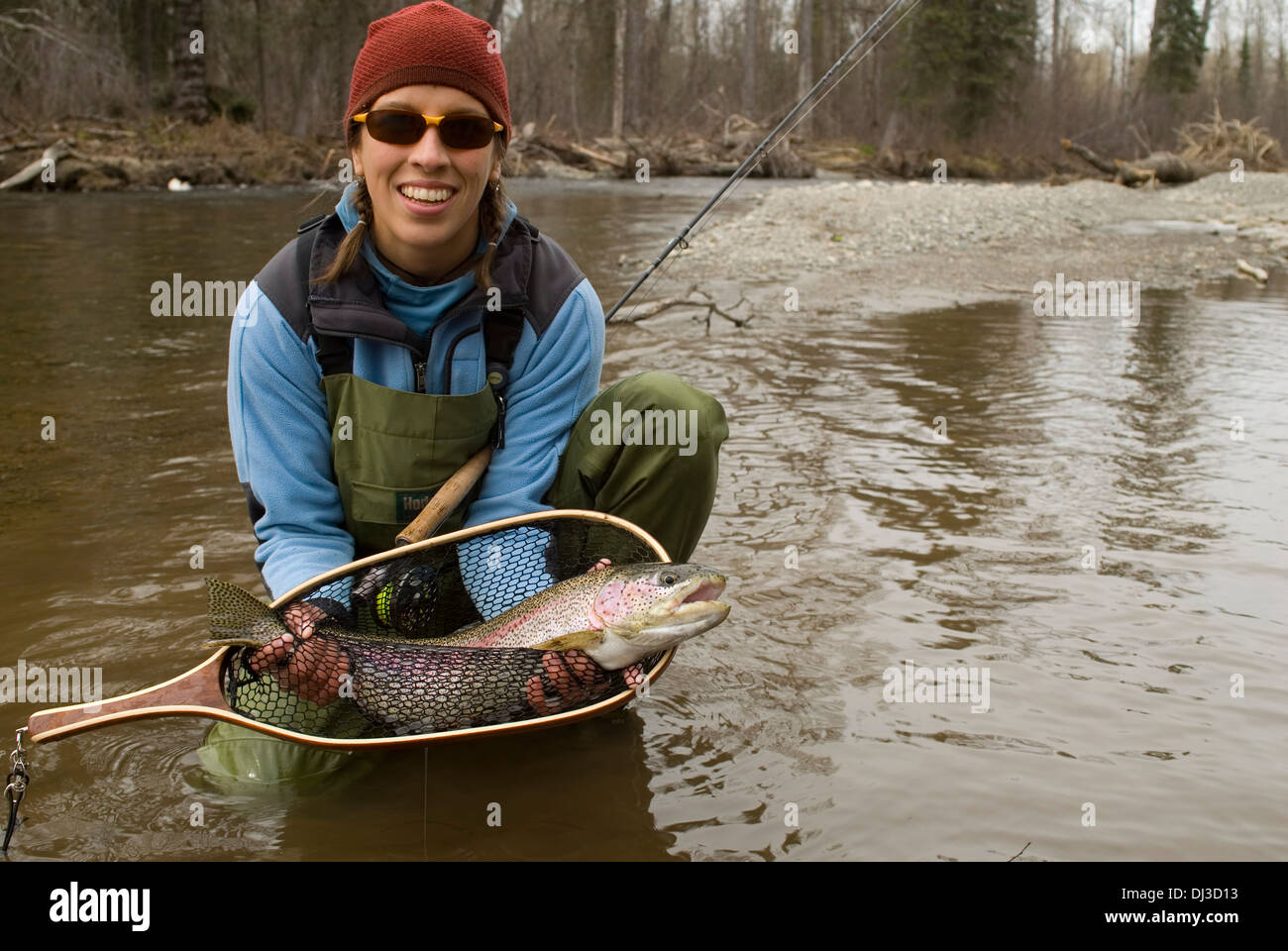A young woman in a cowboy hat holding a fish net shows a cutthroat trout.  stock photo