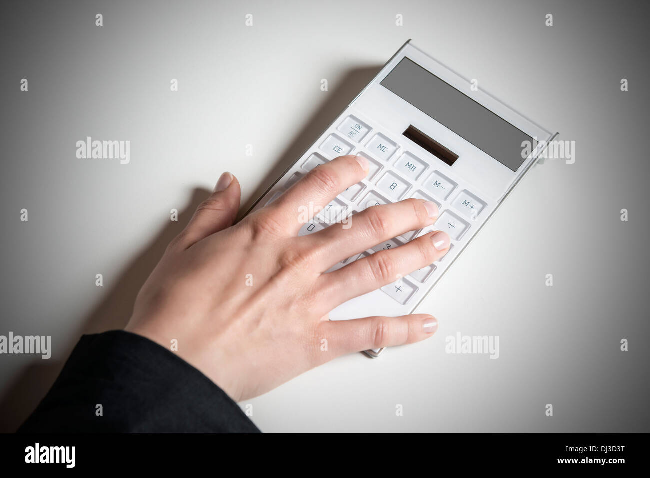 Picture of a female hand typing on a white calculator with empty display Stock Photo