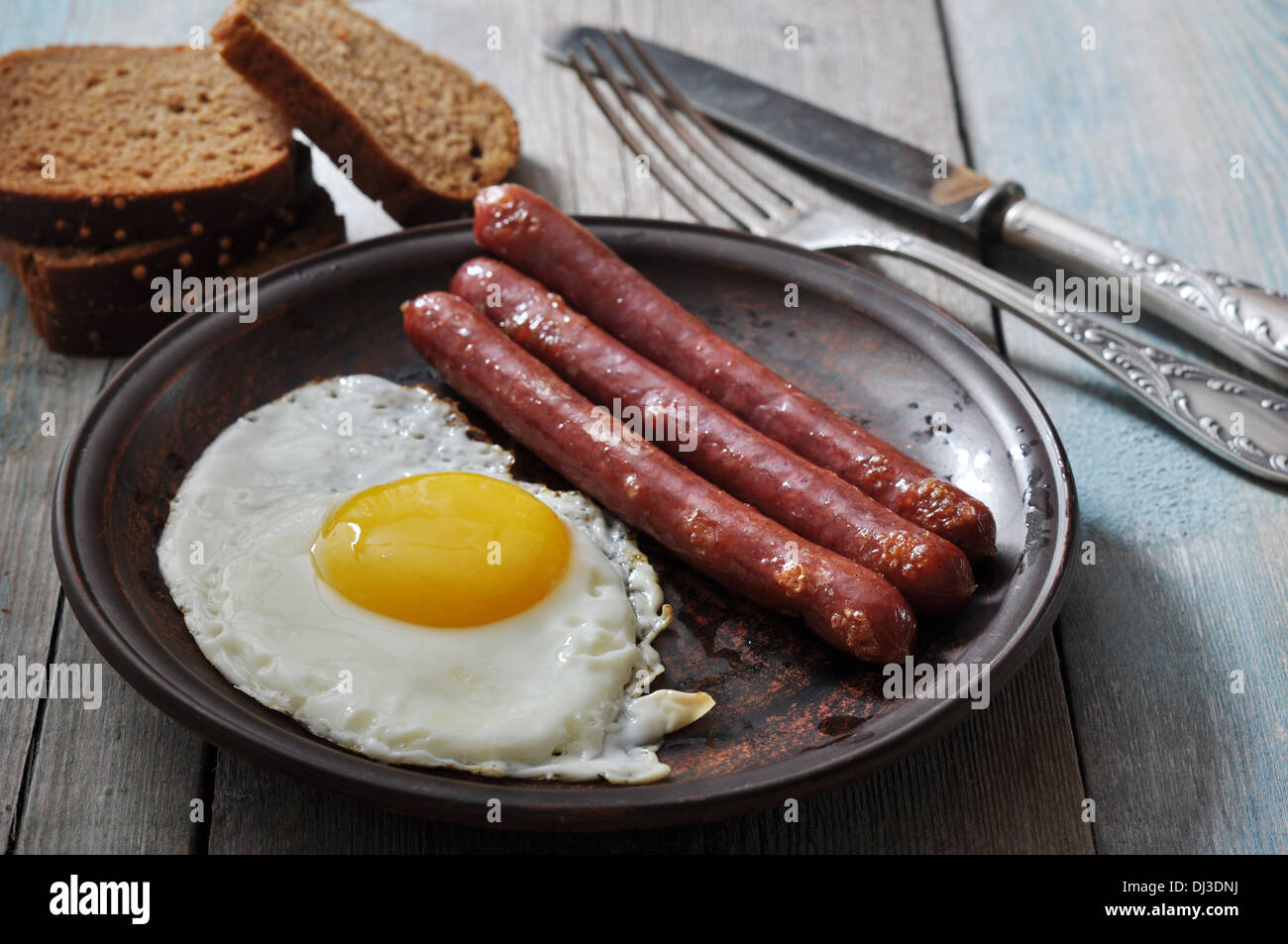 Fried egg with sausages on plate over wooden background Stock Photo