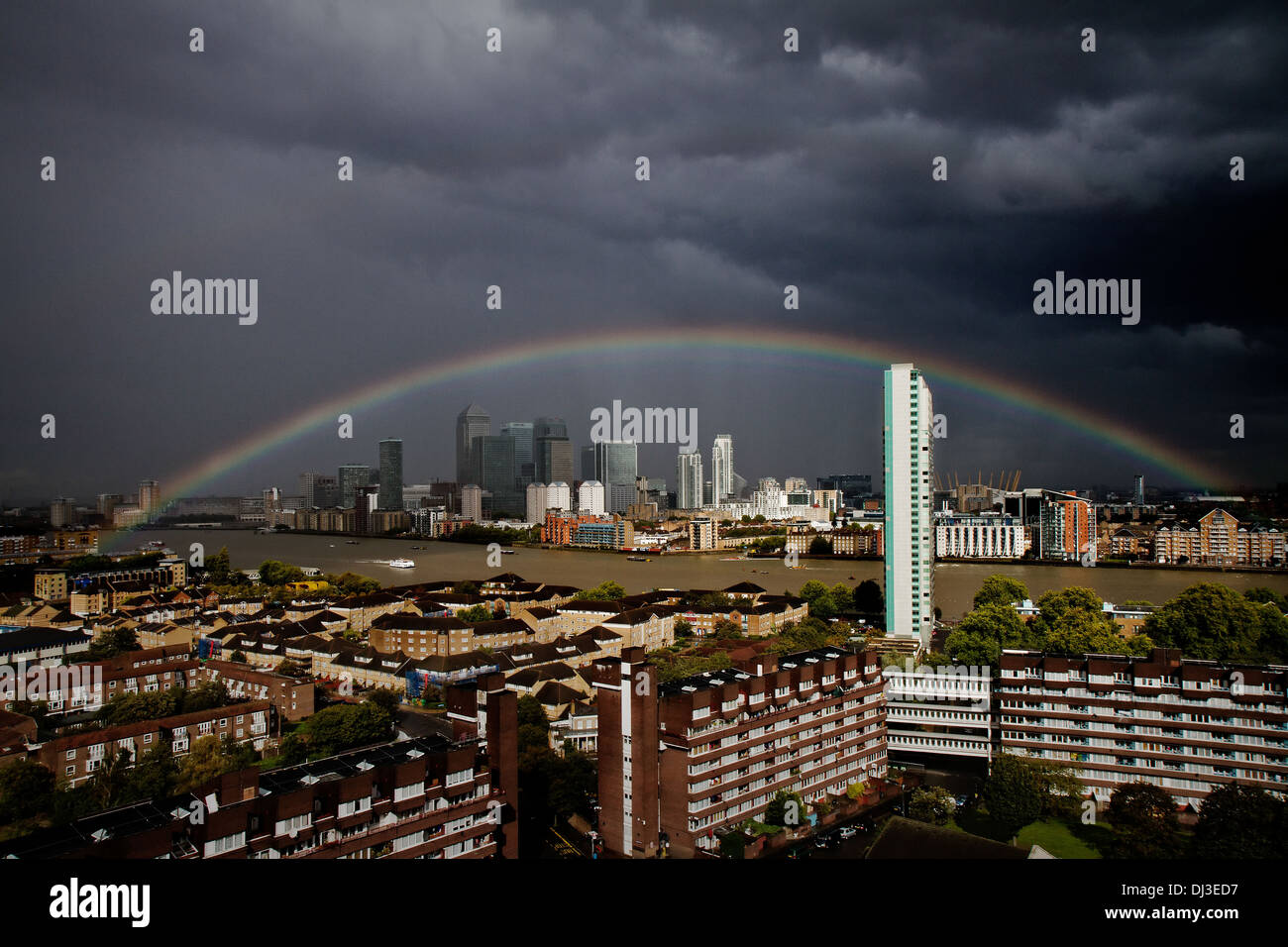 UK Weather: Colourful rainbow breaks during a brief rainstorm over south east London including Canary Wharf business park Stock Photo