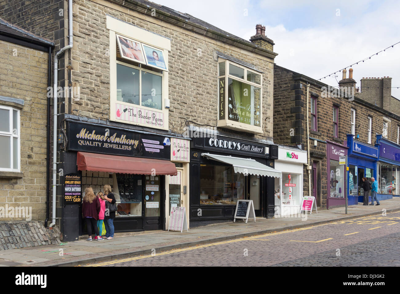 Small local shops and family businesses on Bank Street in the town centre of Rawtenstall, Lancashire with a few shoppers. Stock Photo