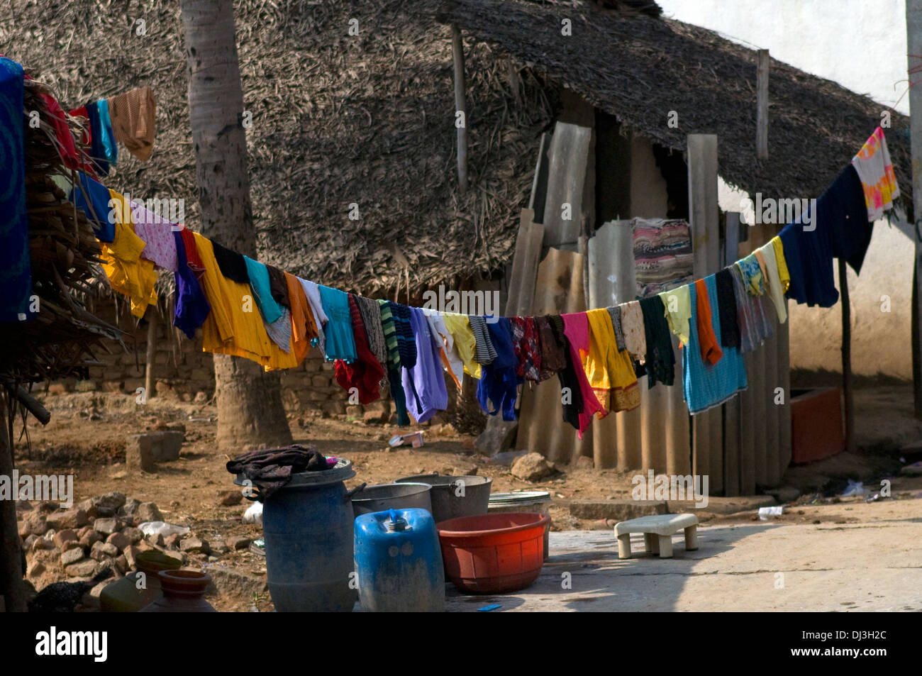 Colourful washing hanging between village huts covered with coconut fronds as walls and roofs Stock Photo