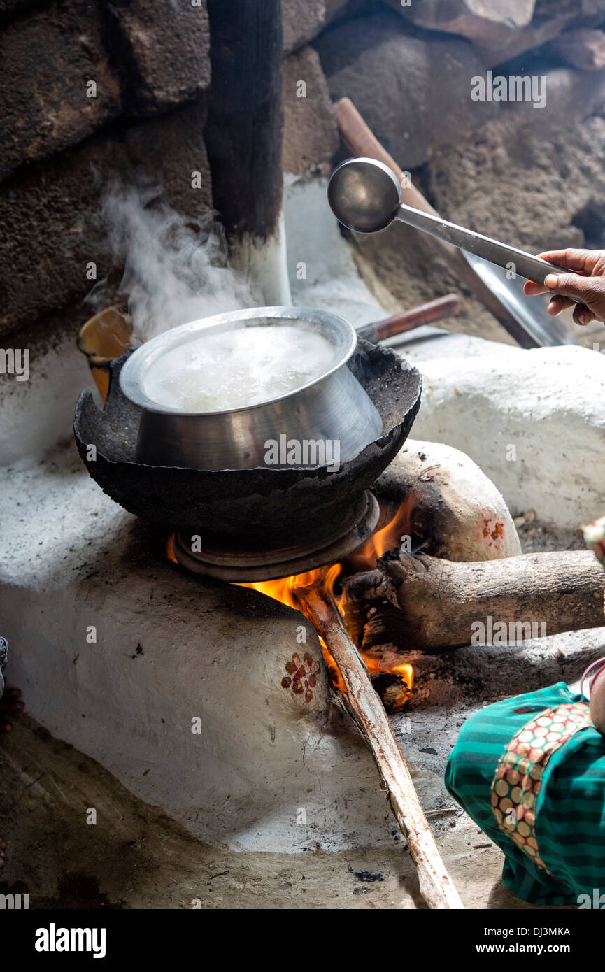 Indian woman cooking rice on an open fire outside her rural Indian