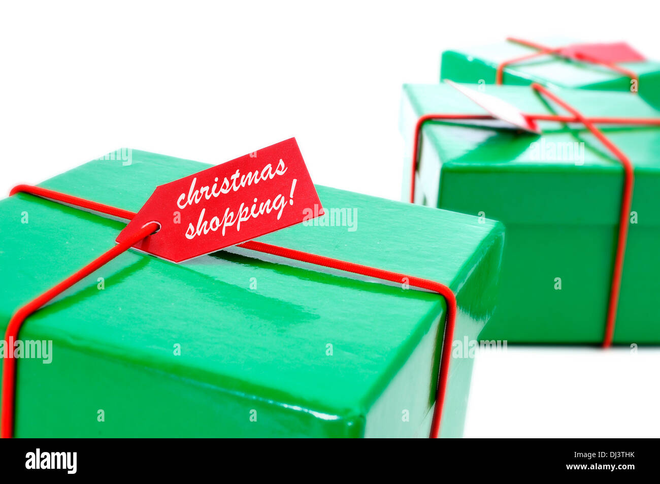 a pile of green and red gifts with a label with the text christmas shopping written in it on a white background Stock Photo