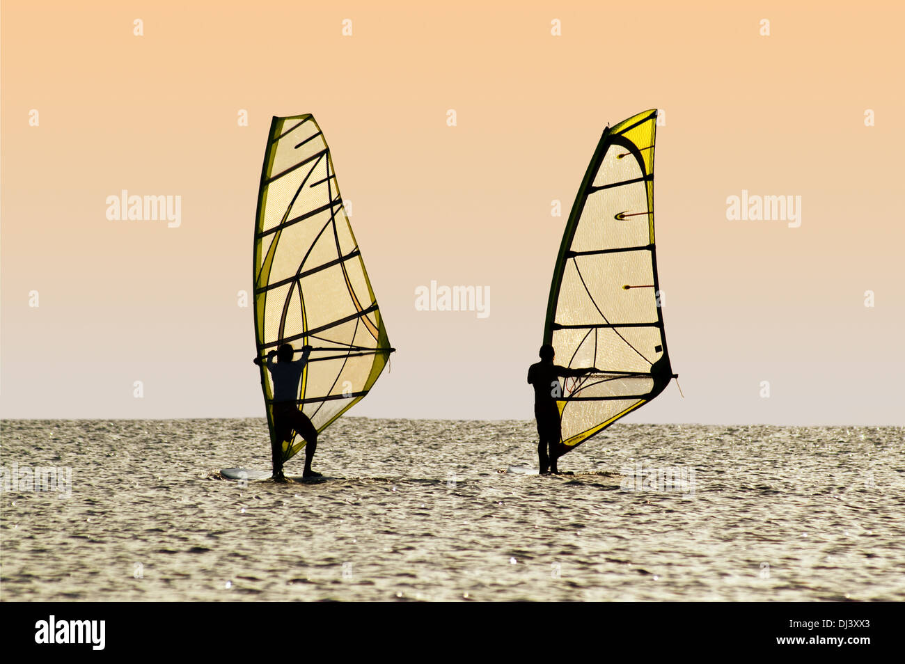 Silhouettes of two windsurfers on waves of a gulf Stock Photo