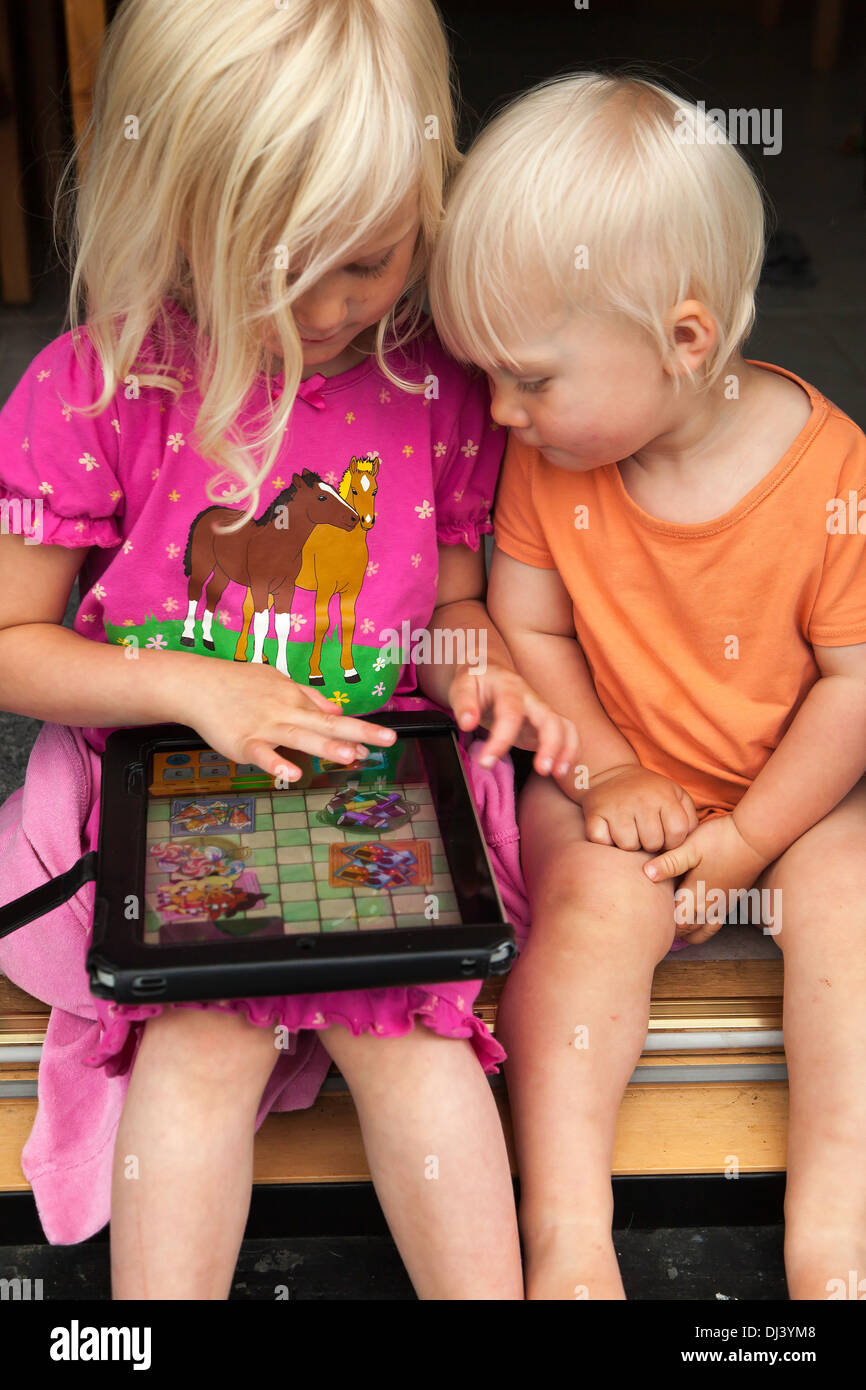 Alicia 5 years old and Theodor 1,5 years old playing computergame on a tablet/Ipad Stock Photo