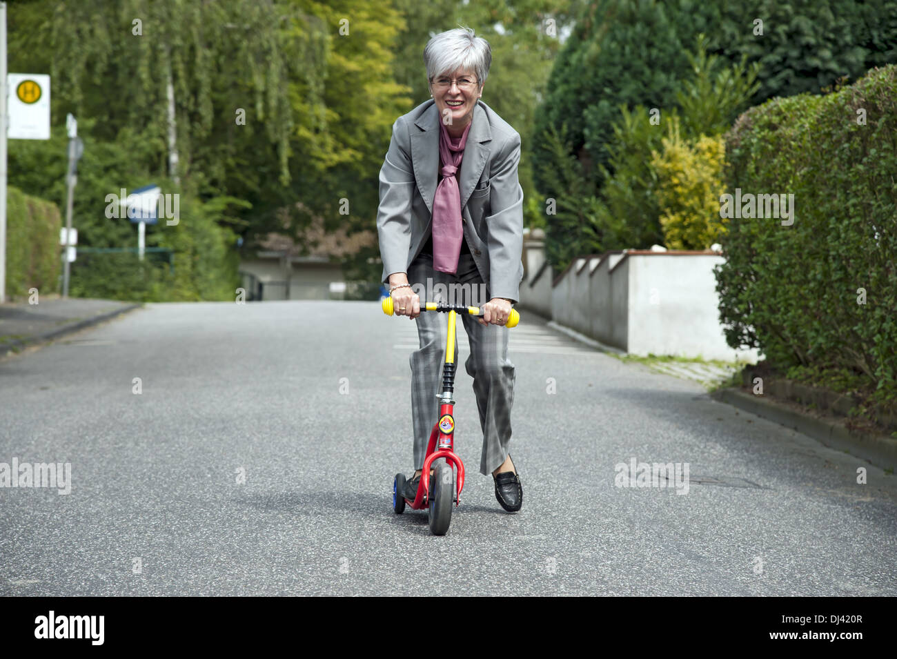elderly woman driving a scooter for children Stock Photo