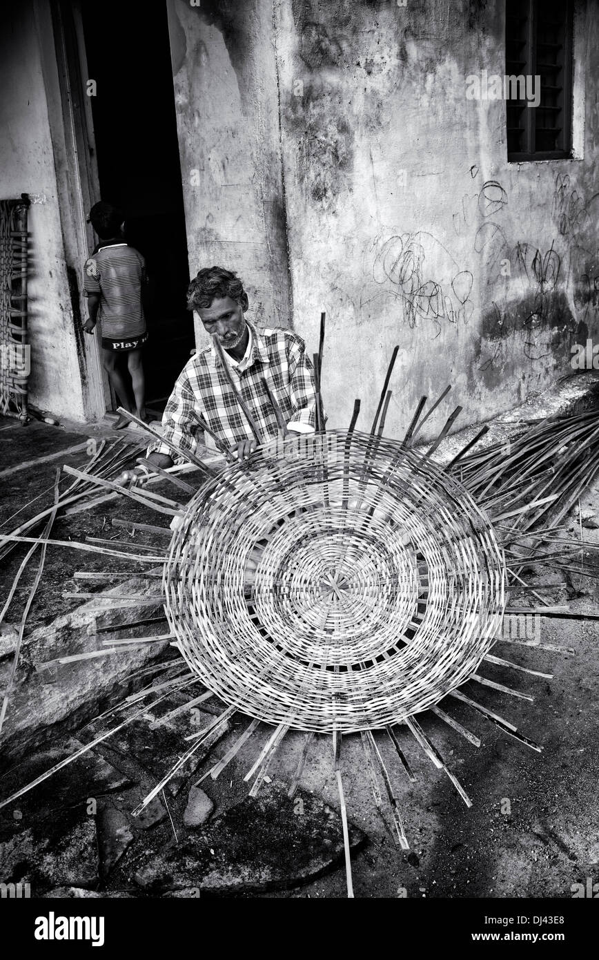 Indian man weaving a traditional goat pen from bamboo in a rural Indian village. Andhra Pradesh, India. Monochrome Stock Photo