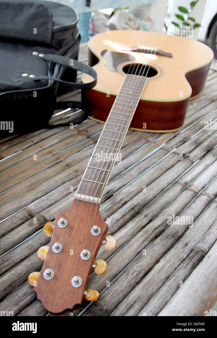 Guitar resting on bamboo desk and the bag was placed beside. Stock Photo