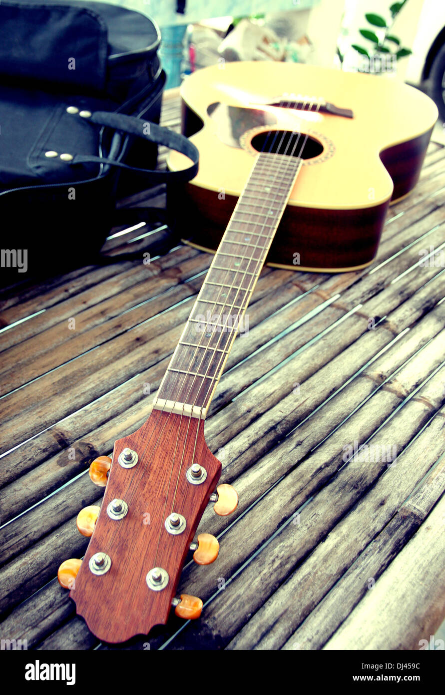 Guitar resting on bamboo desk and the bag was placed beside. Stock Photo