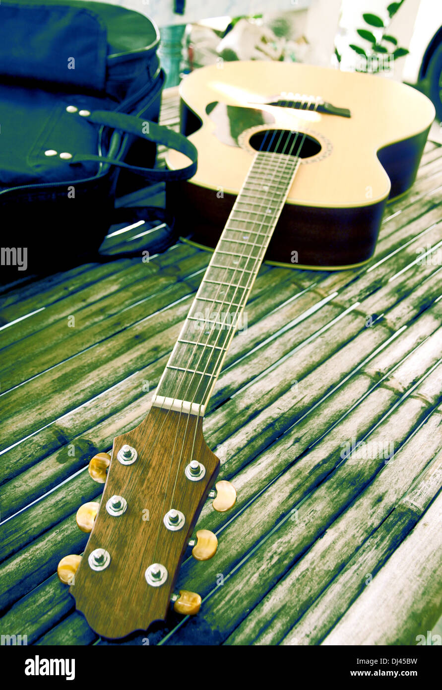 Guitar resting on bamboo desk and the bag was placed beside. Stock Photo