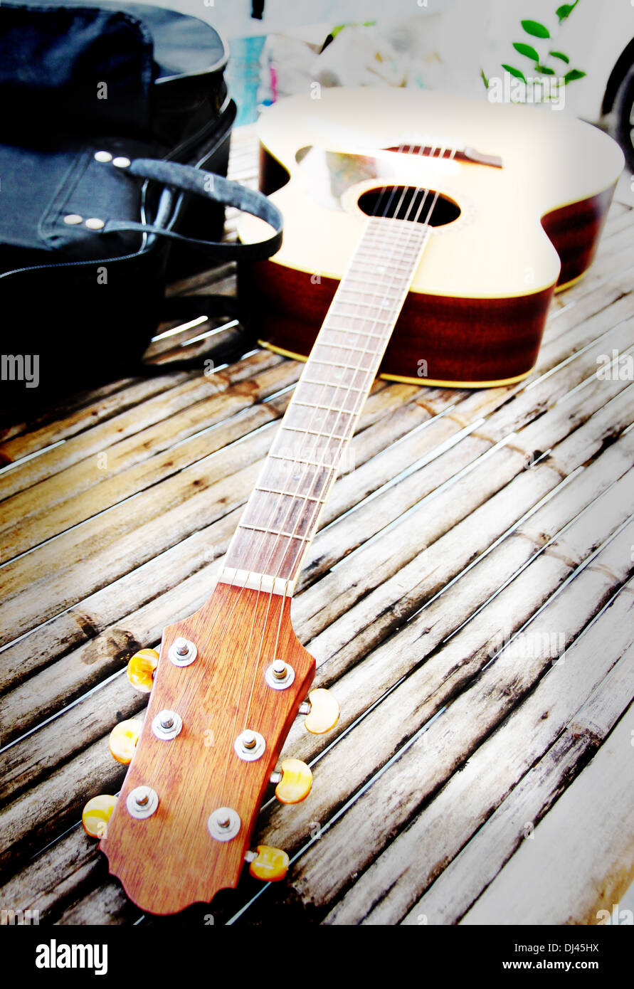 Guitar resting on bamboo desk and the bag was placed beside. Stock Photo