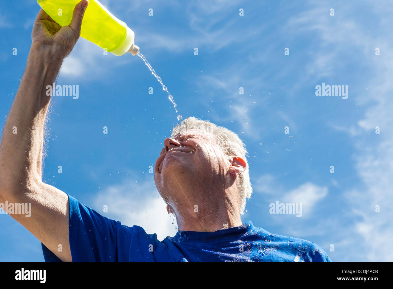 Senior man pouring water over his face to relieve heat exhaustion, United States Stock Photo