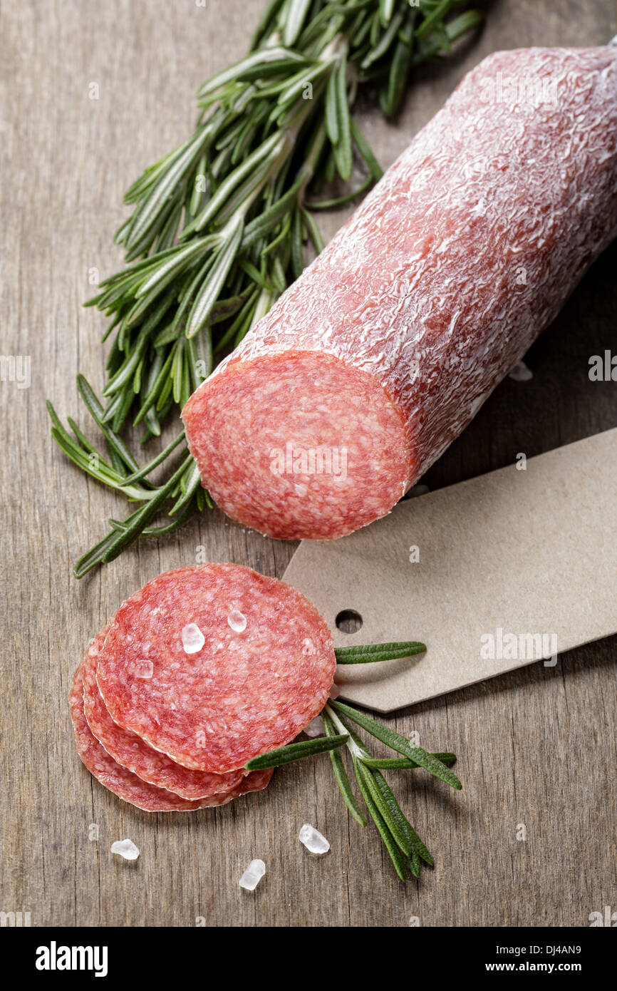 italian salami sausage slices with rosemary and sea salt, wood board