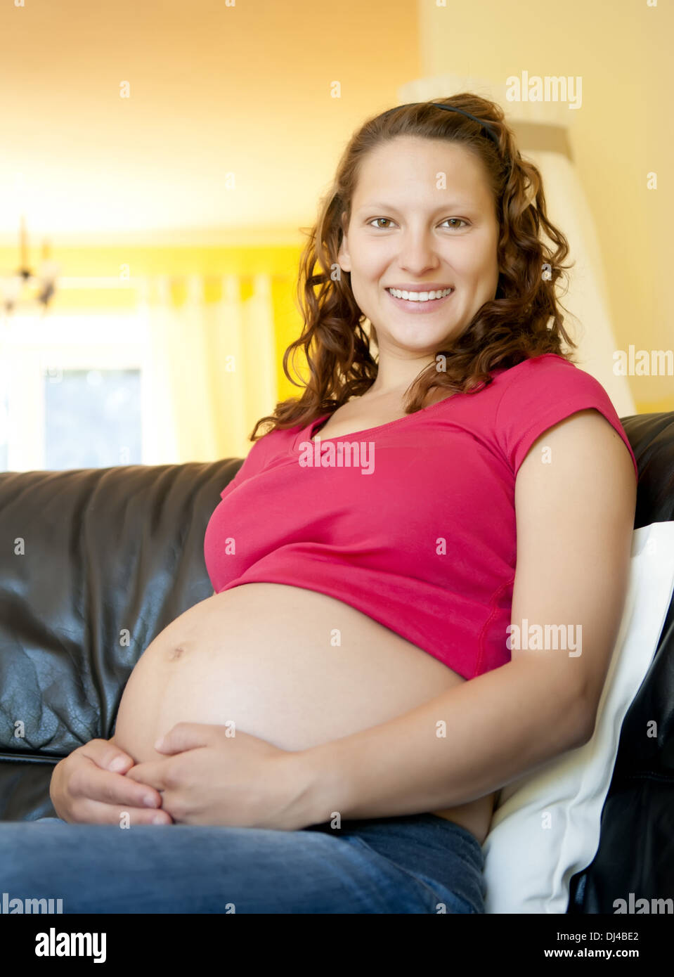 pregnant young woman sitting on a couch Stock Photo Alamy