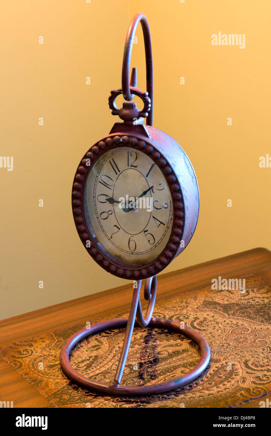 Antique decorative metal clock atop wooden desk Stock Photo