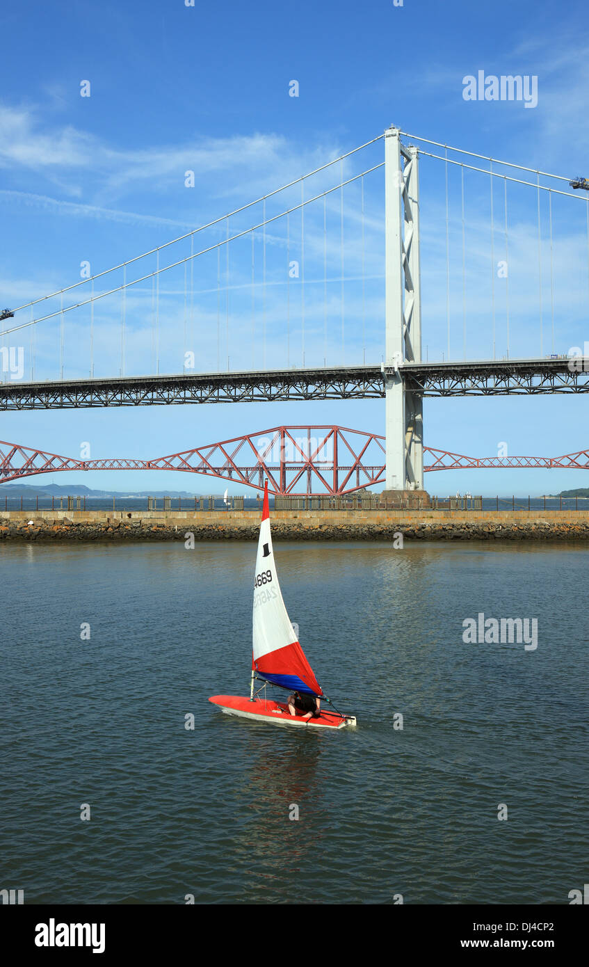 A Topper sails on the River Forth with the Forth road and rail bridges in the background Stock Photo
