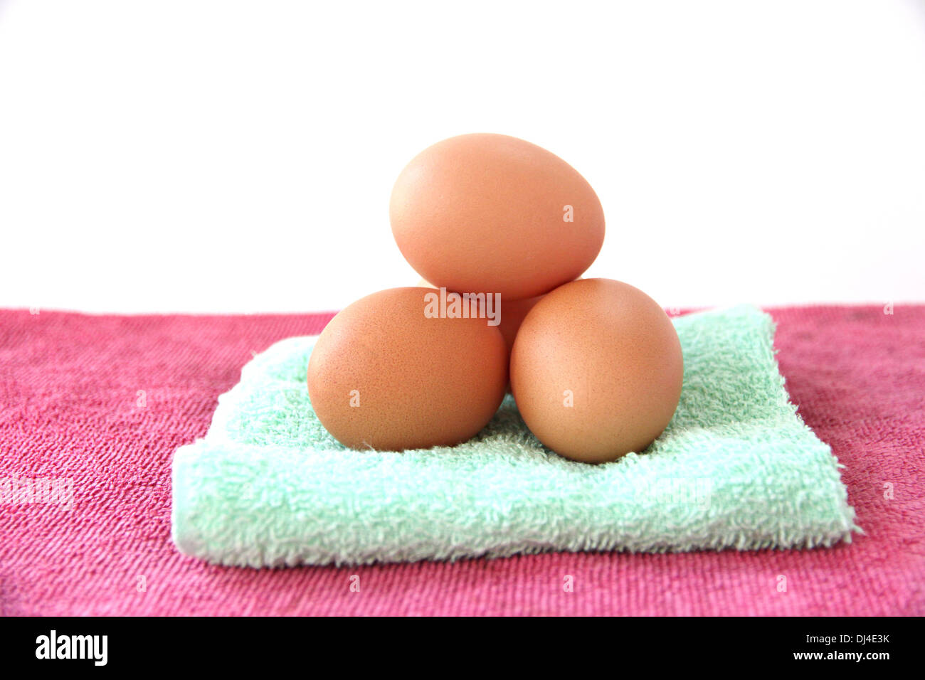 The picture Eggs on green and pink towel in white background. Stock Photo