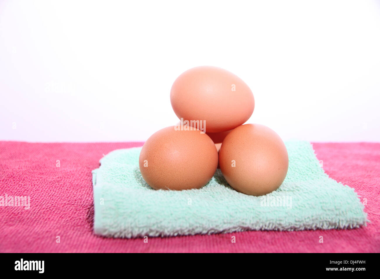 The picture Eggs on green and pink towel in white background. Stock Photo