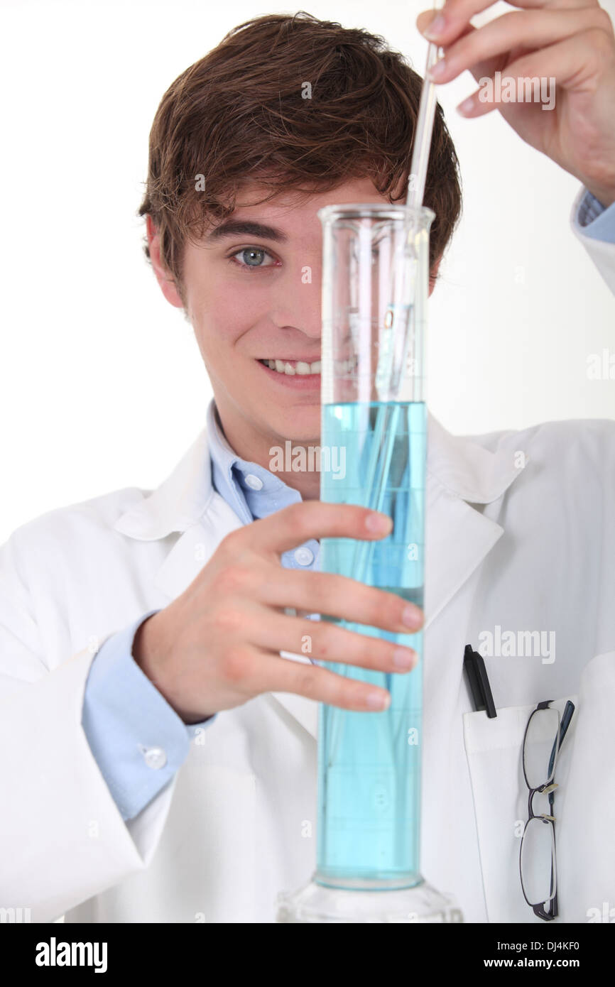 Young chemistry student stirring blue liquid in a glass graduated