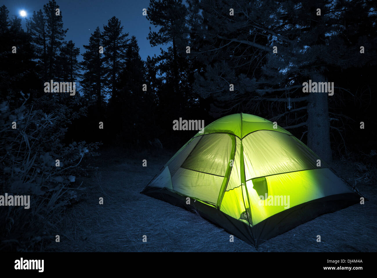 Small Camping Tent Illuminated Inside. Night Hours Campsite. Recreation and Outdoor Photo Collection. Stock Photo