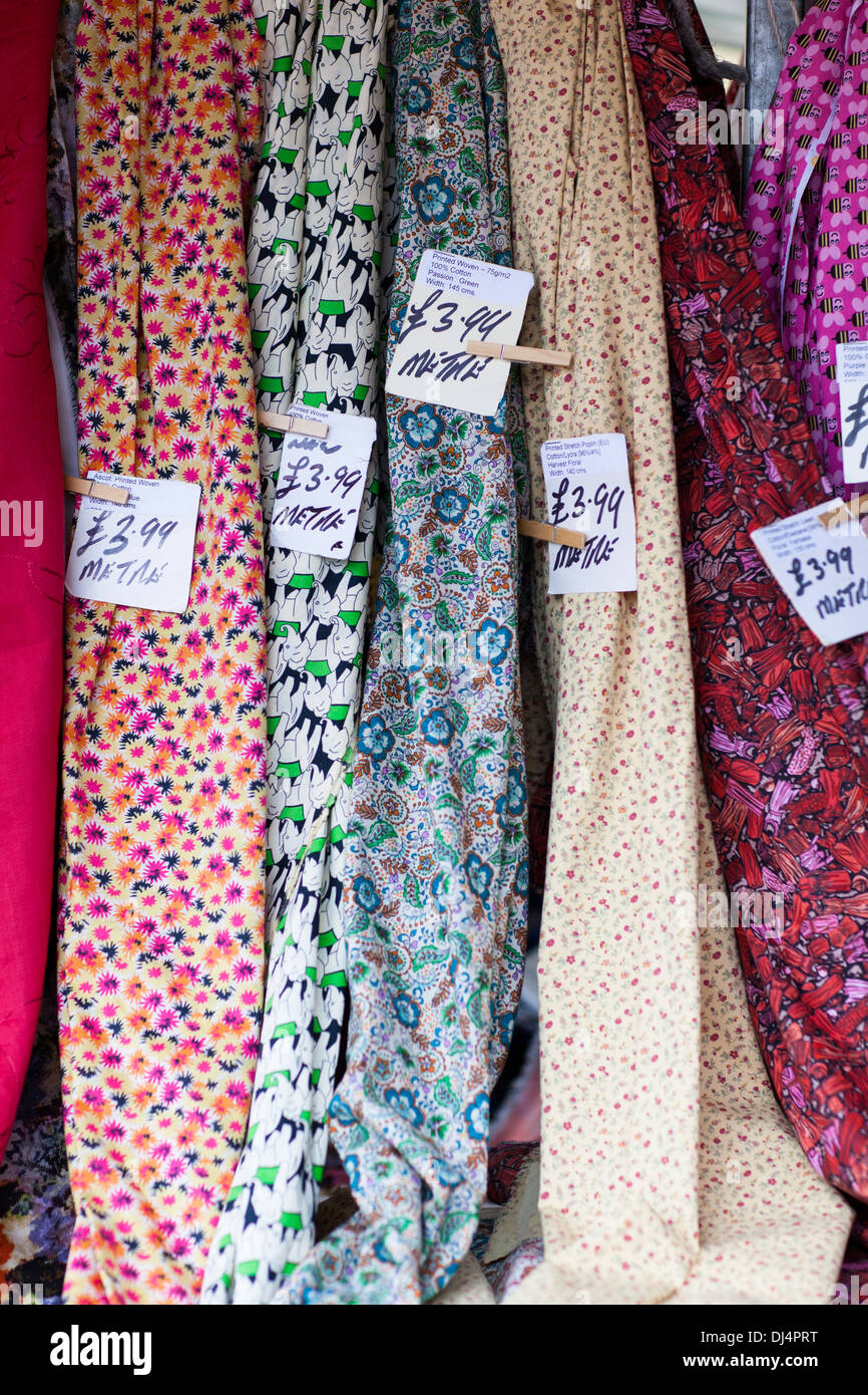 Bolts of patterned cloth on a market stall. Stock Photo