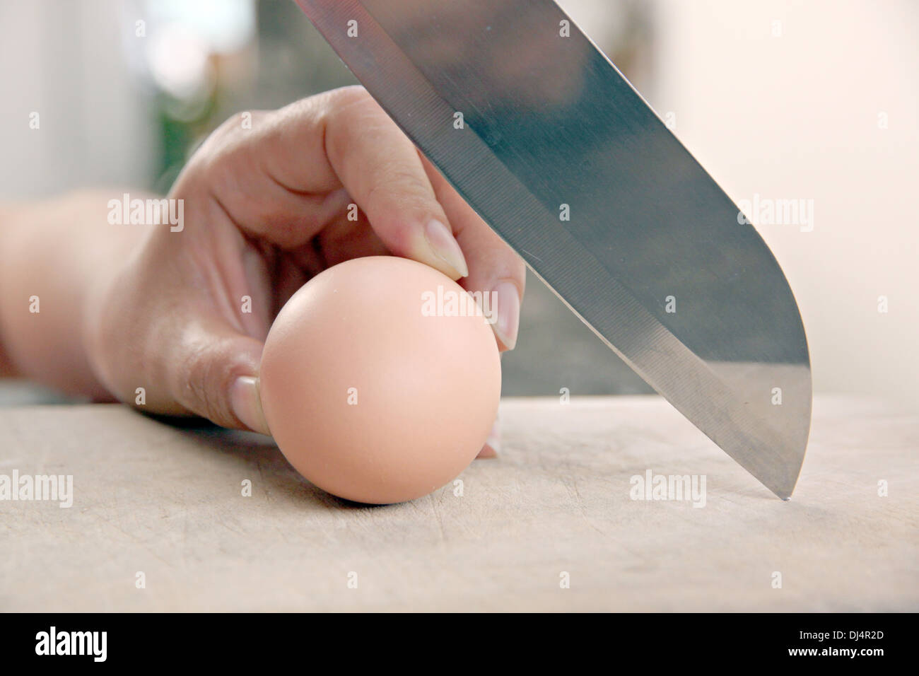 Hand that holds a knife and Eggs that are about to sliced. Stock Photo