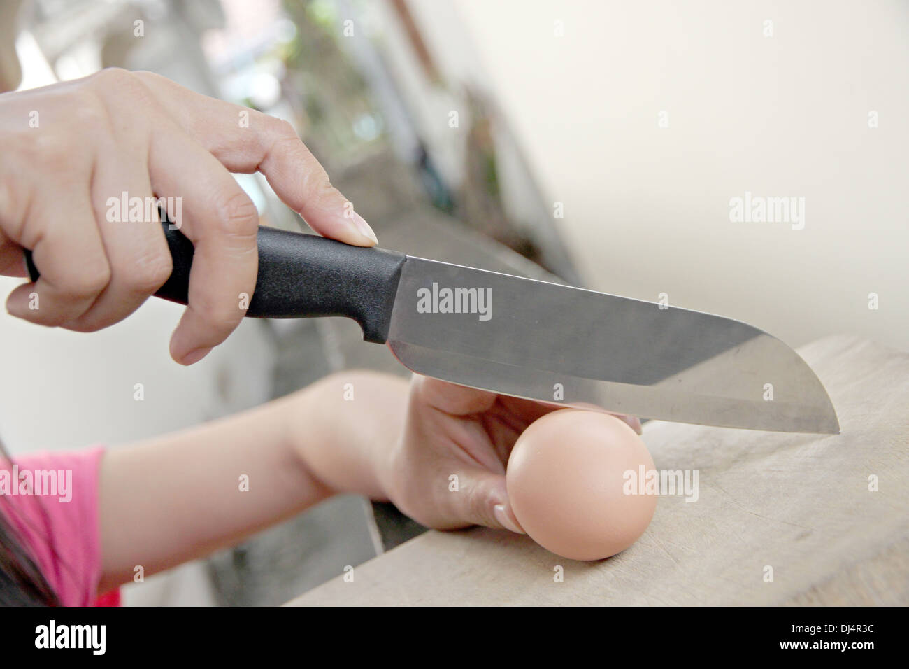 Hand that holds a knife and Eggs that are about to sliced. Stock Photo