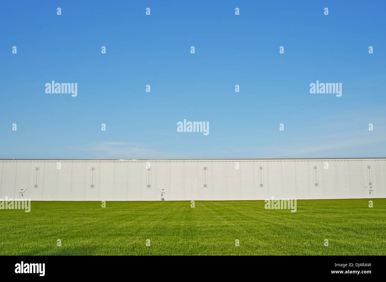 Large Warehouse Building and the Grass Field. Industrial Zone Stock