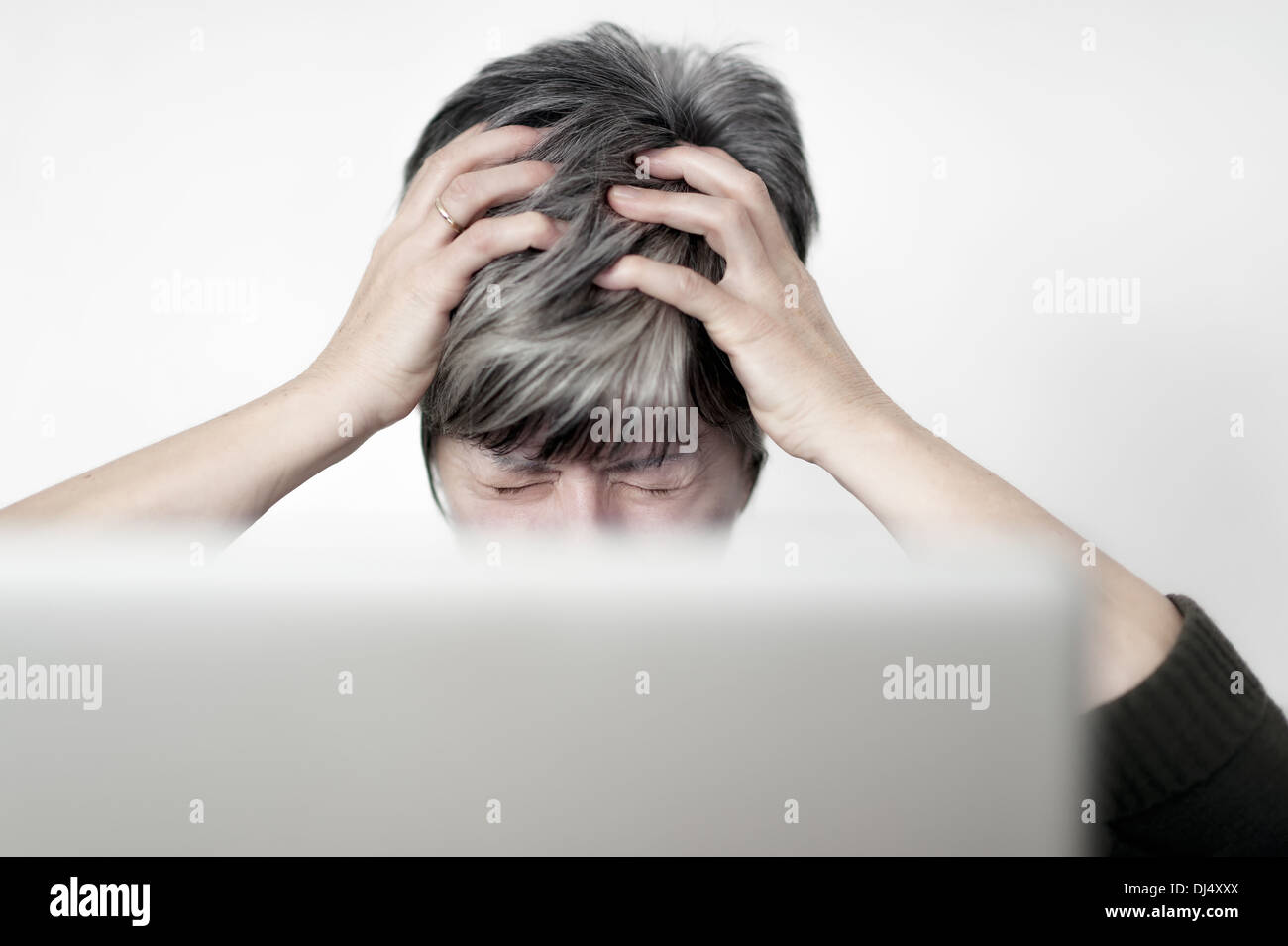 stressed woman sitting behind a laptop Stock Photo