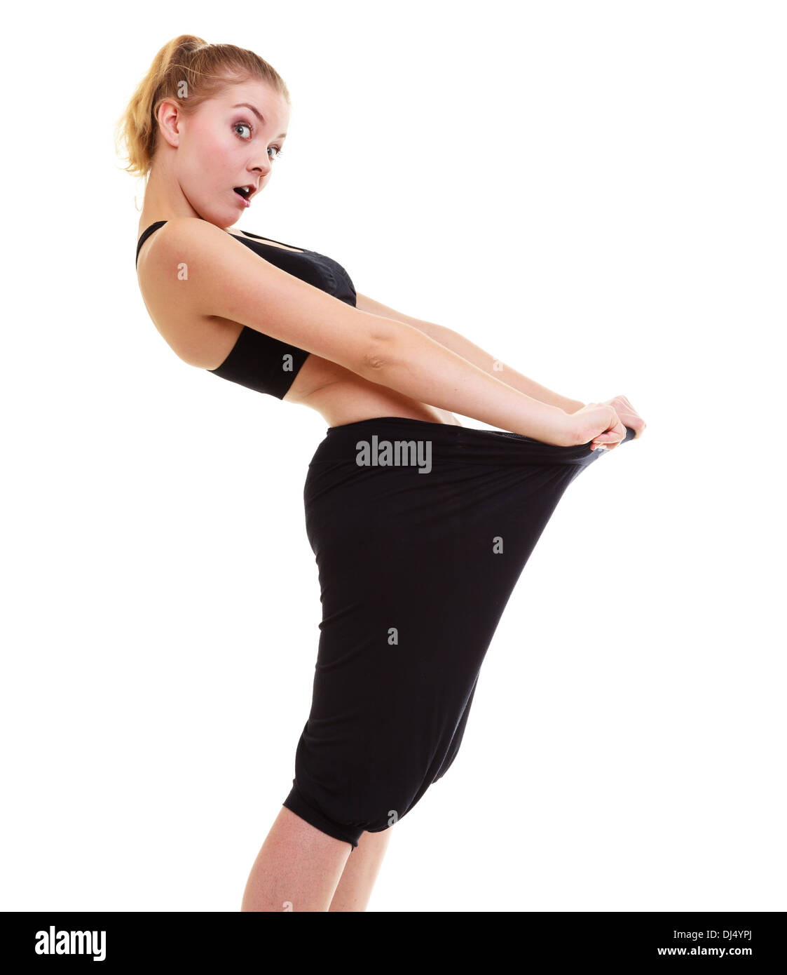 Weight loss. Excited woman fitness girl with big pants, showing how